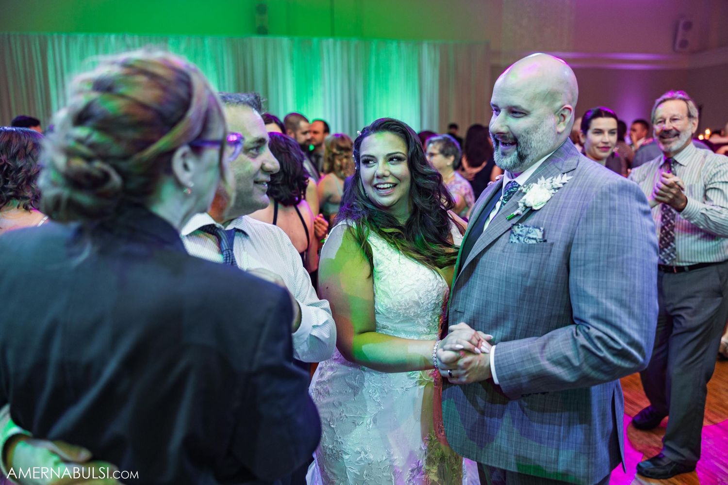 Couple dancing together under green and purple reception lighting.