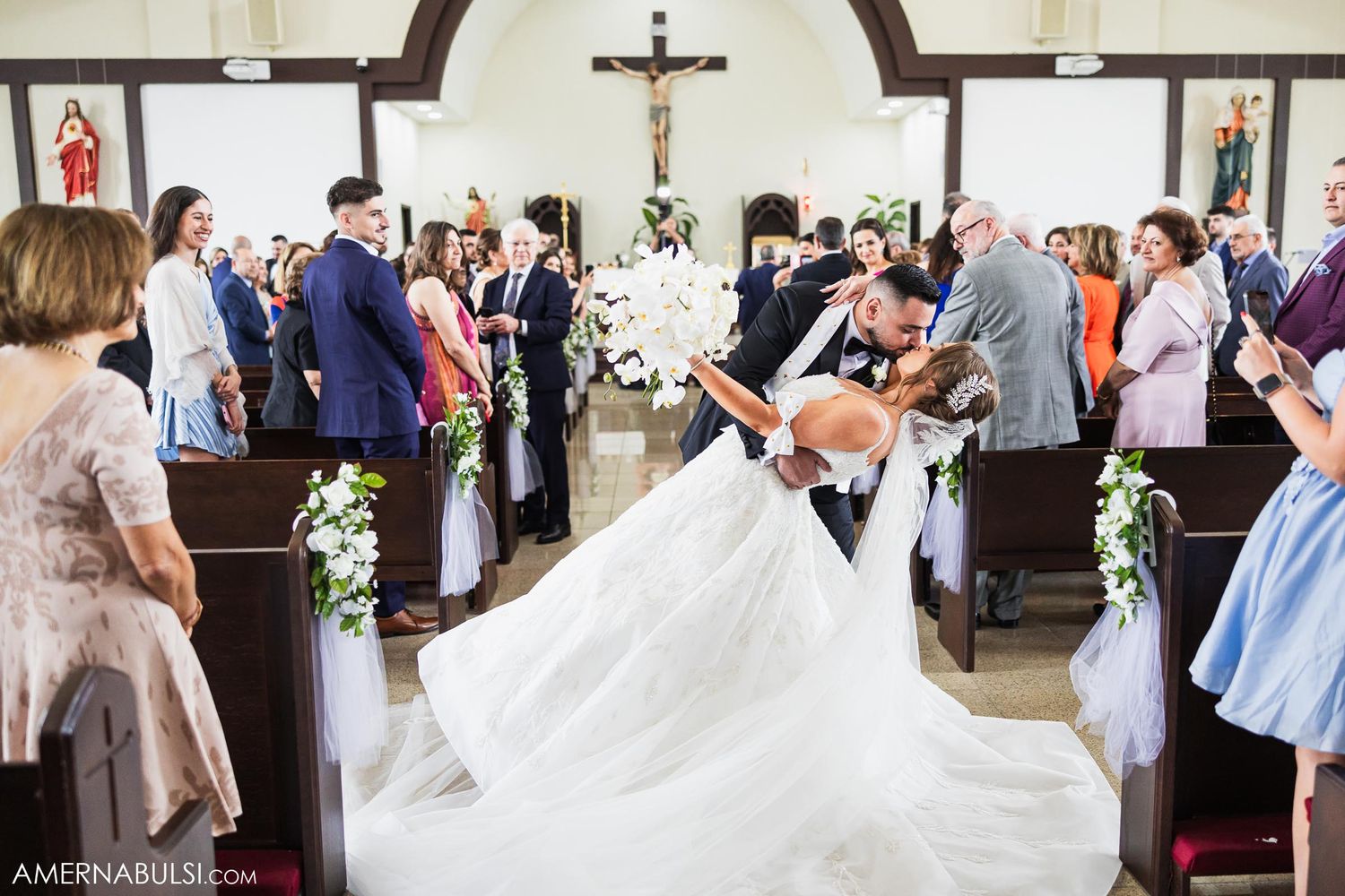 Wedding dress billows dramatically during celebratory recessional in church aisle.