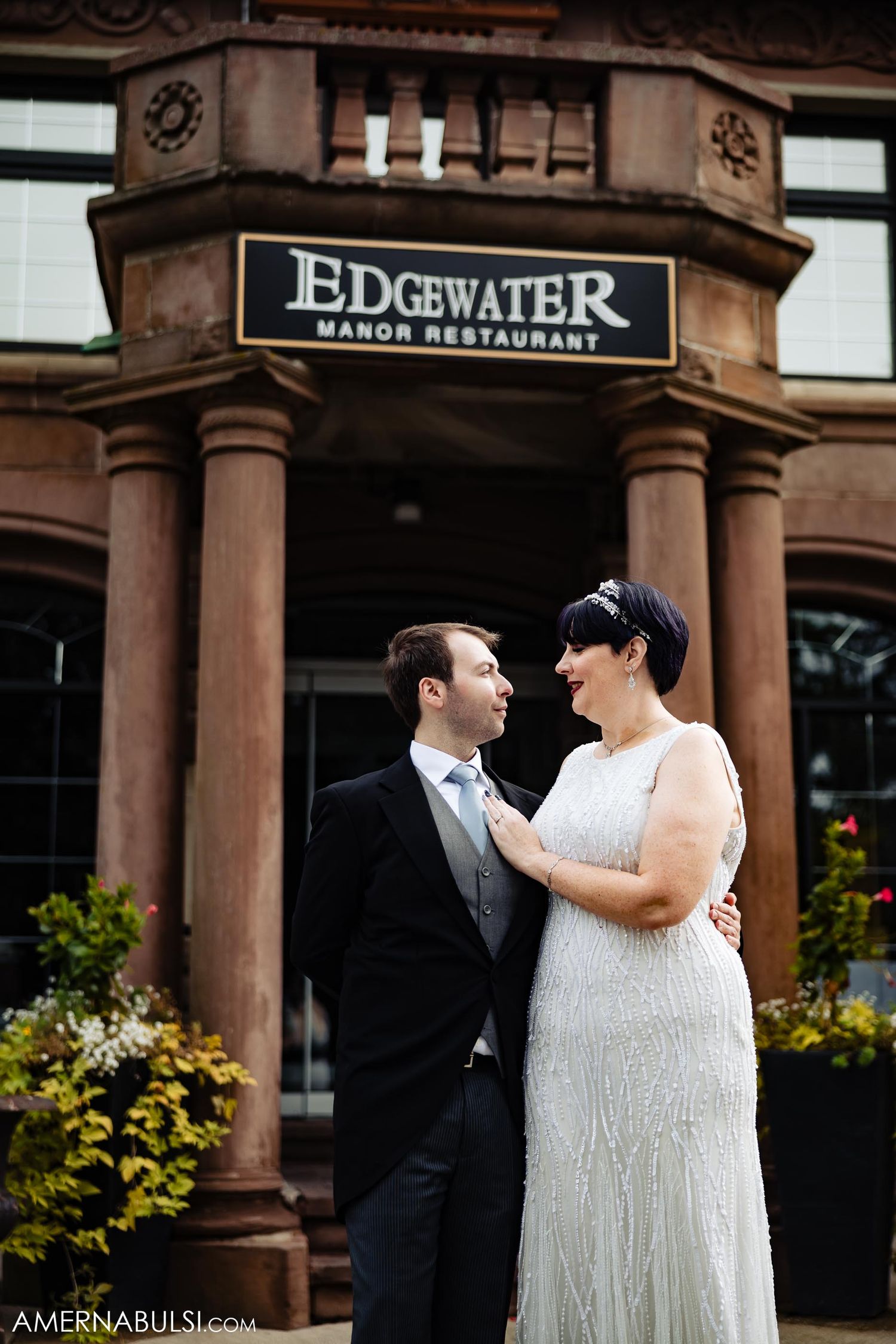 Elegant couple poses outside historic Edgewater Manor Restaurant entrance.
