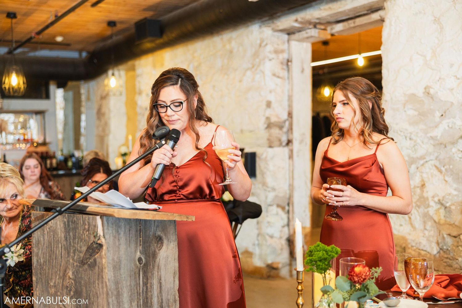 Bridesmaids in rust-colored dresses give emotional speeches during wedding reception.