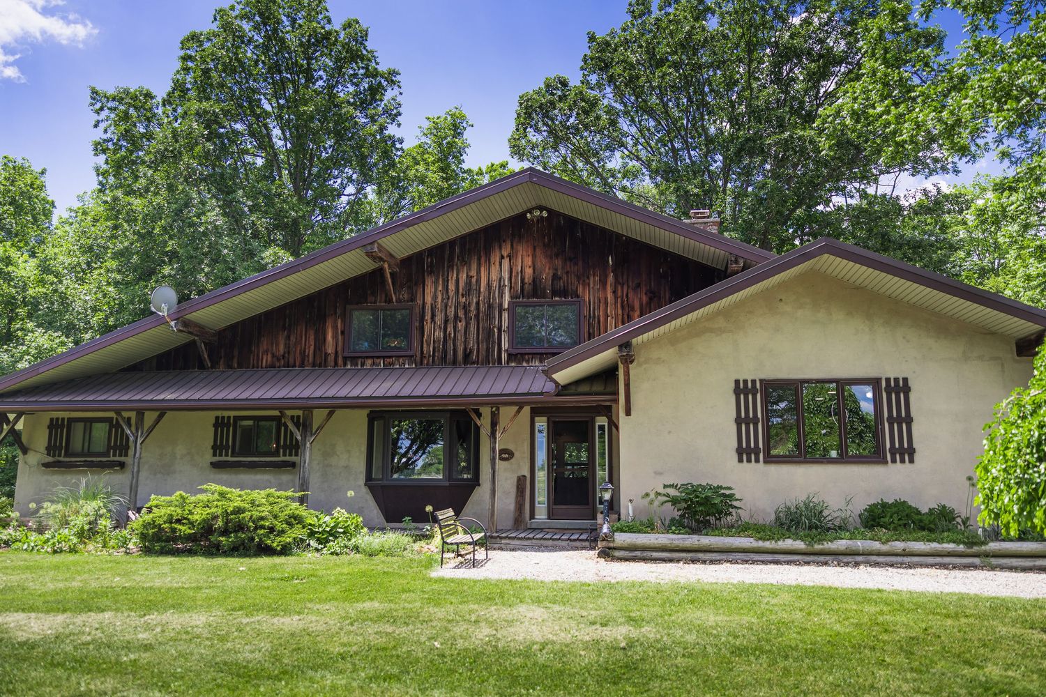 Charming mid-century home with wood and stucco exterior surrounded by lush green trees.
