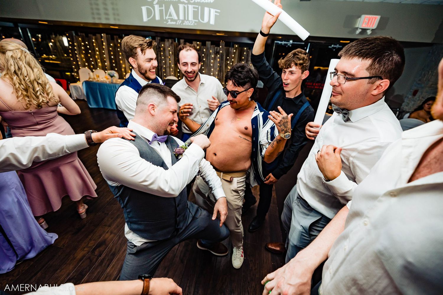 Energetic group of guests dancing and celebrating at indoor reception venue.