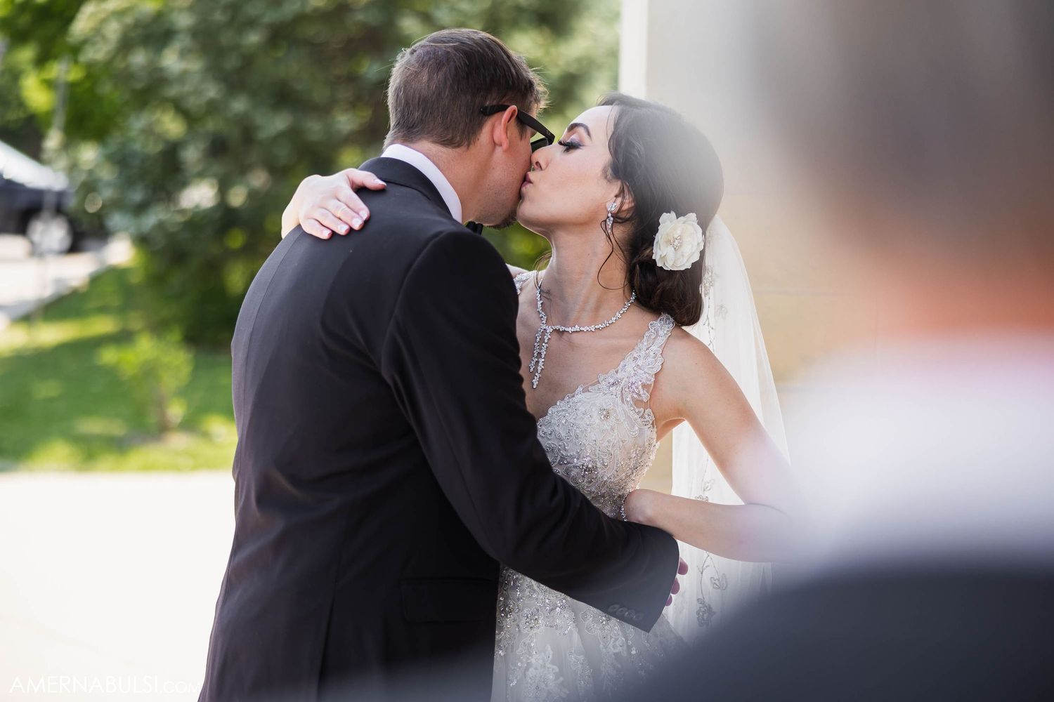 A romantic wedding kiss captured during an outdoor summer ceremony.