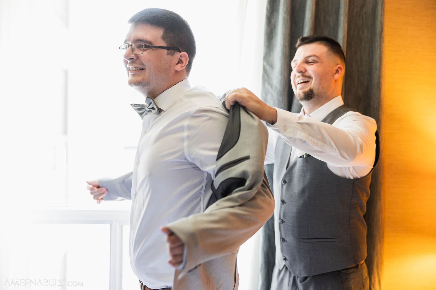 Two people in formal attire helping each other get dressed for an event.