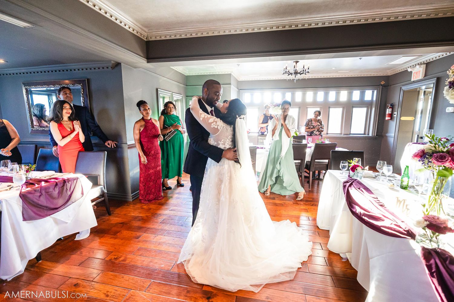 A romantic first dance at a wedding reception with guests looking on in elegant attire.
