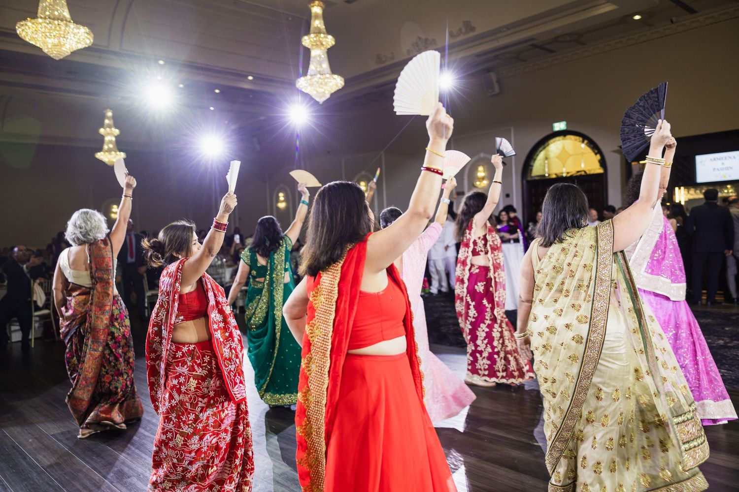 Traditional Indian wedding fashion show featuring colorful lehengas and formal wear on display in a ballroom setting.