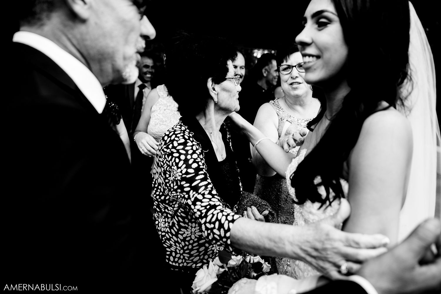 Black and white candid shot of wedding guests celebrating and dancing at a reception.