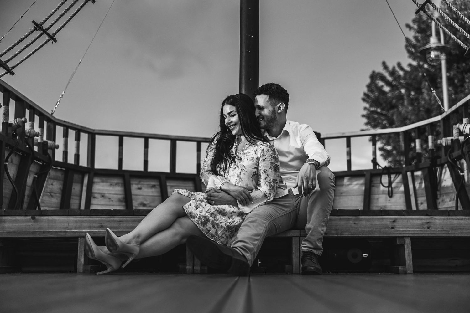 Black and white photo of couple sitting on wooden bench outdoors.