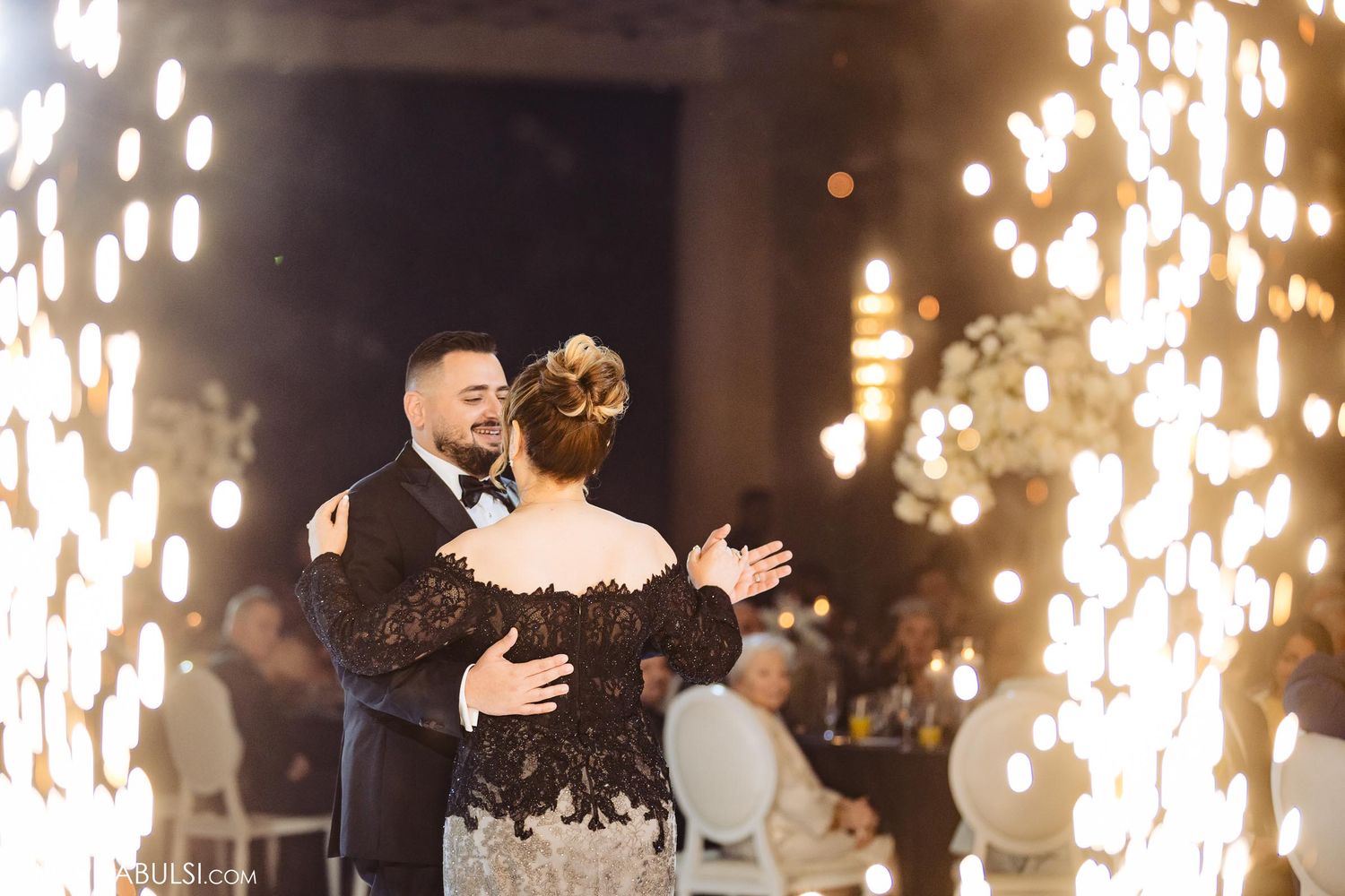 Couple dancing surrounded by dramatic sparkler effects during their wedding celebration.