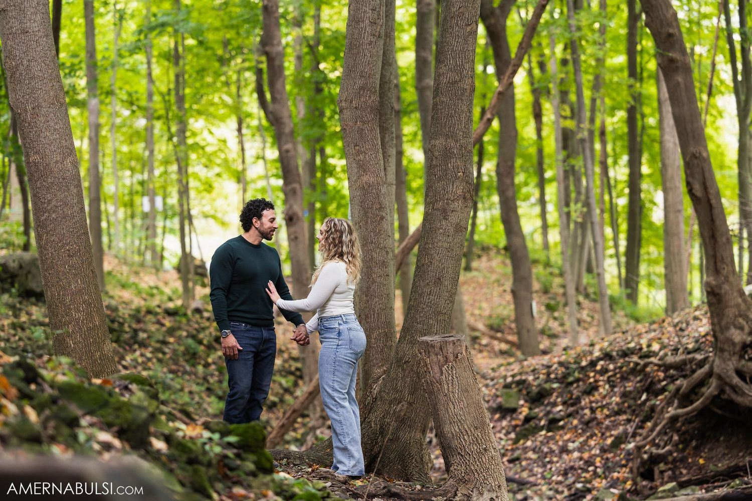 A couple explores a wooded trail together on an autumn afternoon.