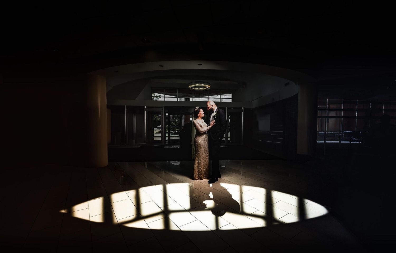Artistic spotlight wedding portrait in dark urban setting.