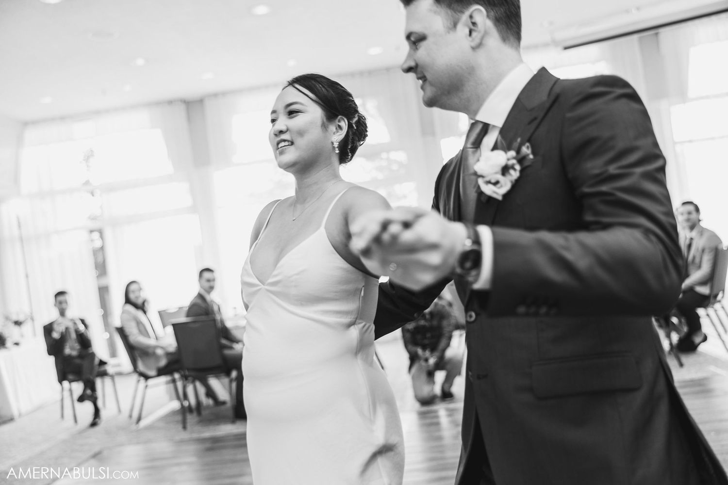 A couple shares their first dance as newlyweds during a wedding reception in a bright ballroom.