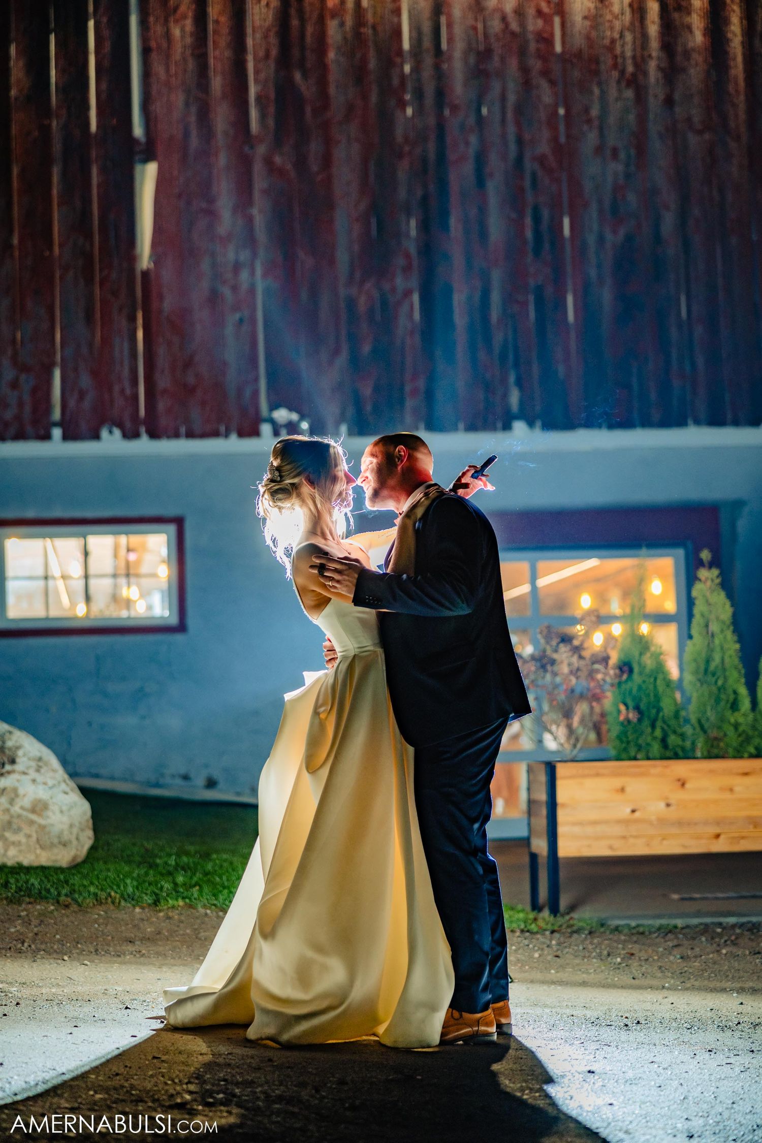 Dancing at night outside a rustic barn venue with illuminated windows visible.