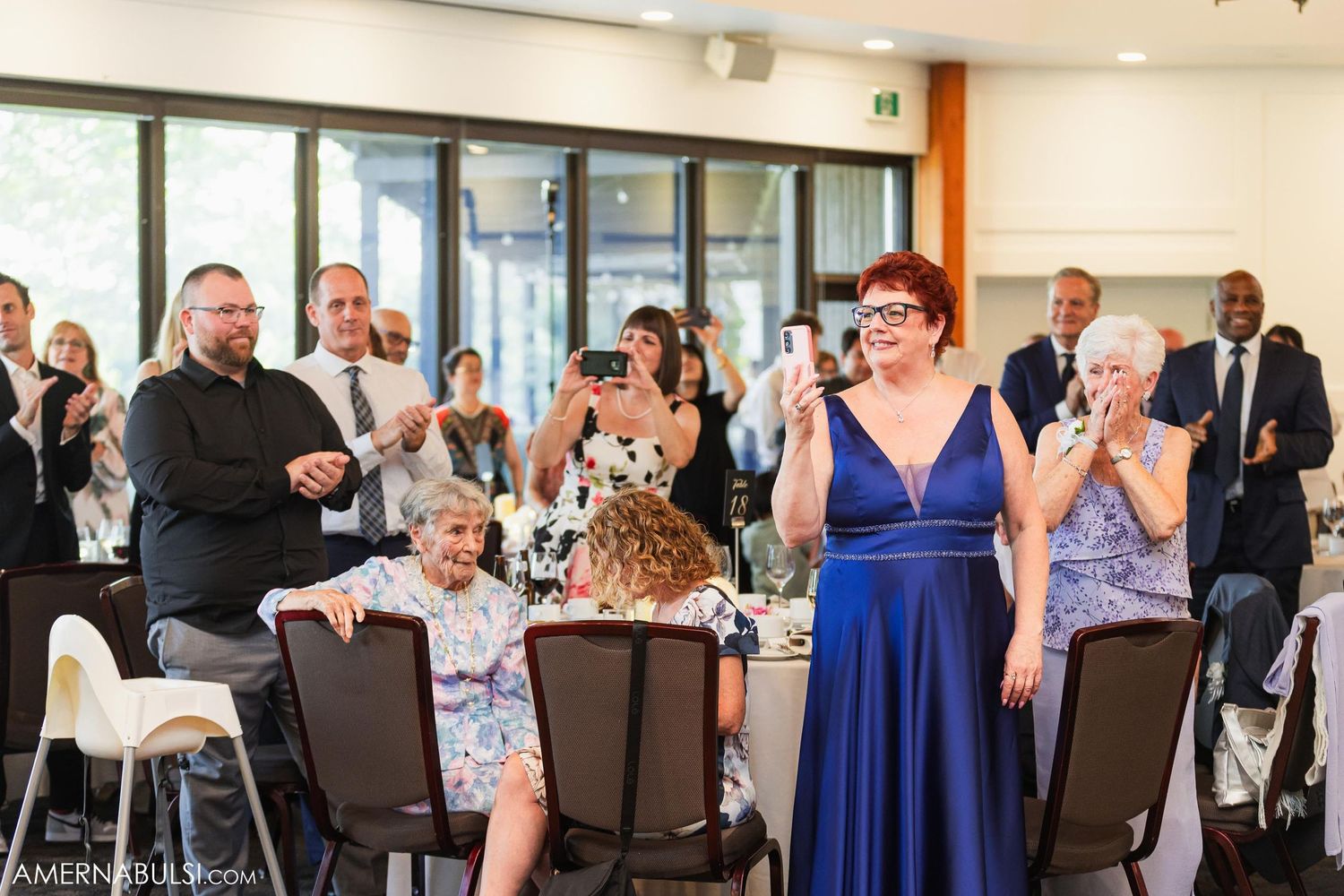 Wedding reception guests applaud during celebratory moment.