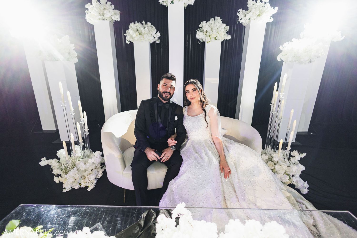 Elegant wedding scene with white floral arrangements and candlesticks decorating a black and white themed reception space.