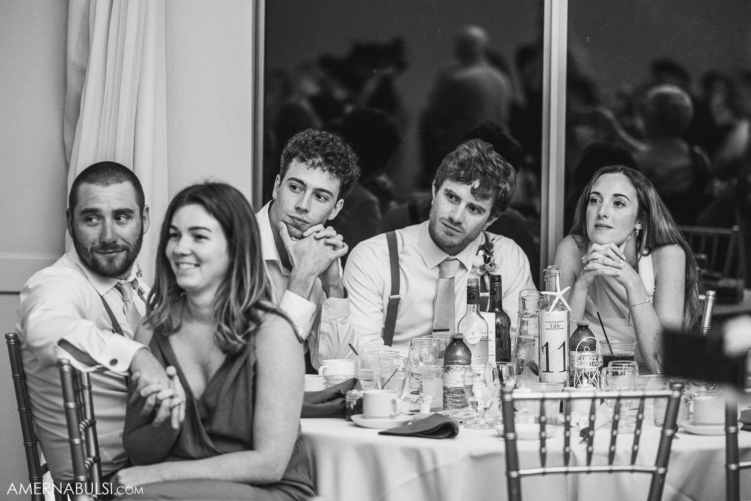 Wedding guests enjoy a celebration dinner at tables with formal place settings and glowing candlelight.