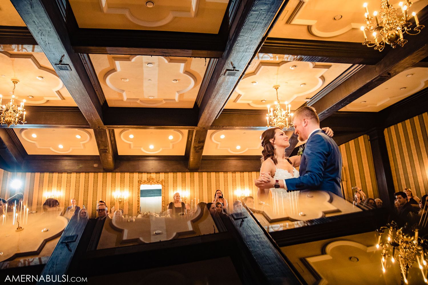 Illuminated ceiling panels and chandeliers create warm ambiance in an elegant reception venue.