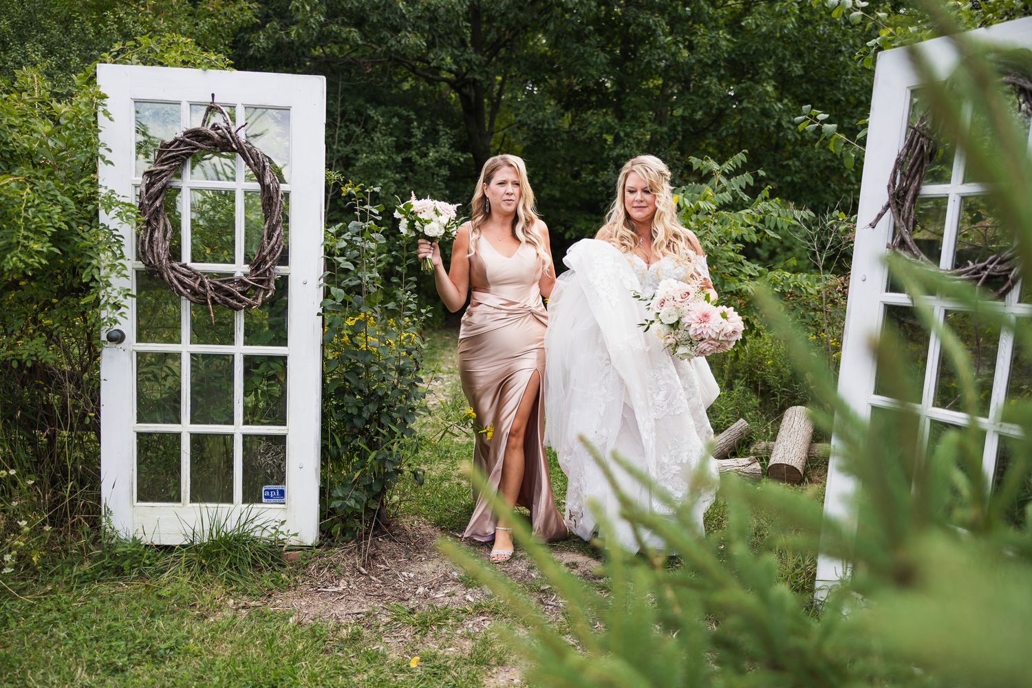 Garden wedding pathway lined with white window frames and lush greenery on a sunny day.