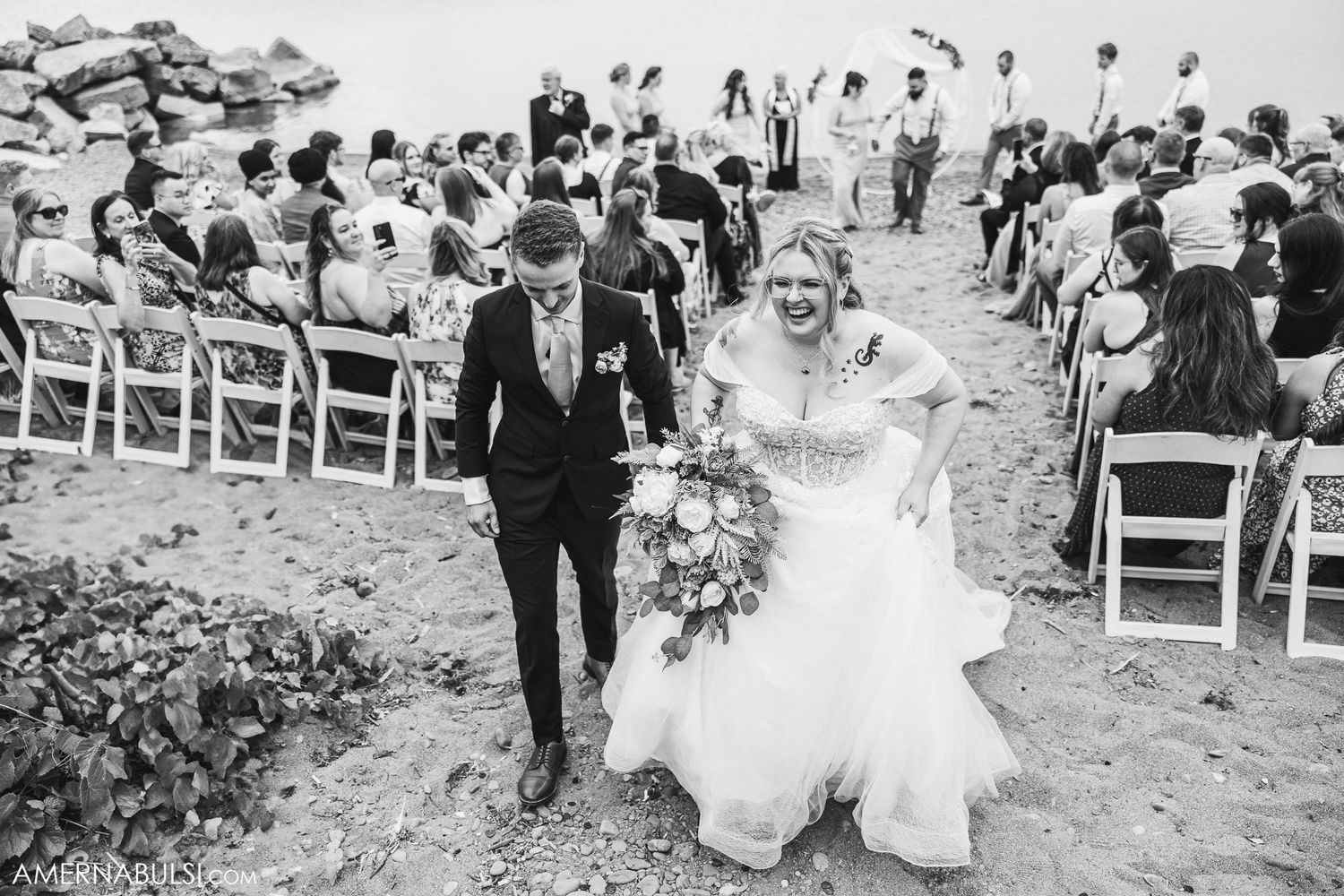 Black and white photo of wedding ceremony recessional with guests throwing flower petals.