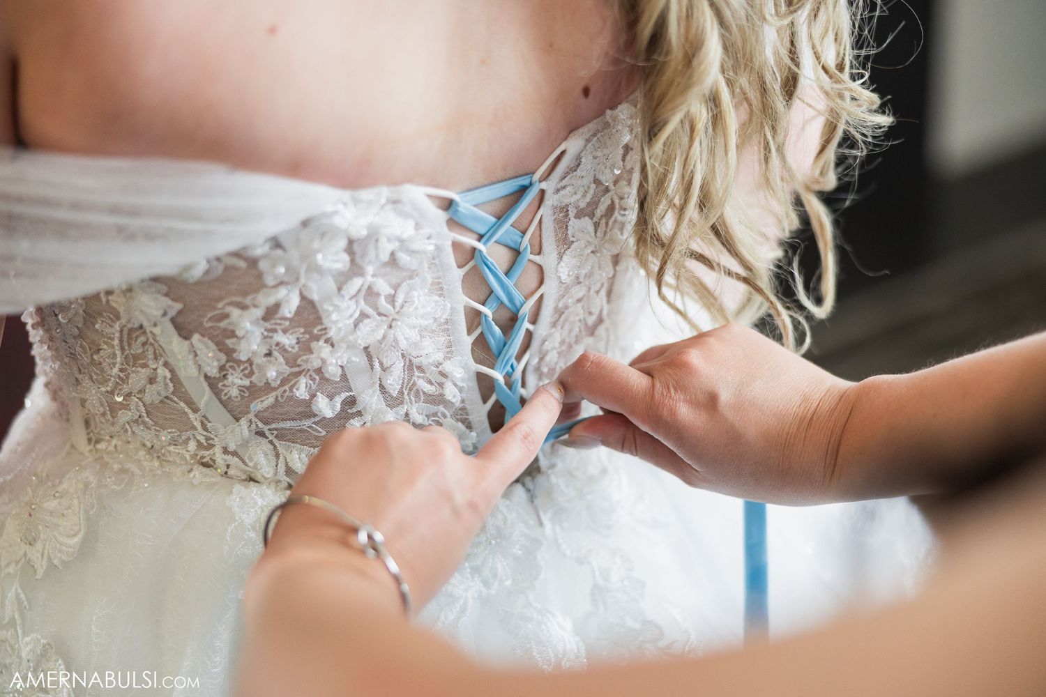 Detailed shots of lace and beading on a white wedding gown being prepared.