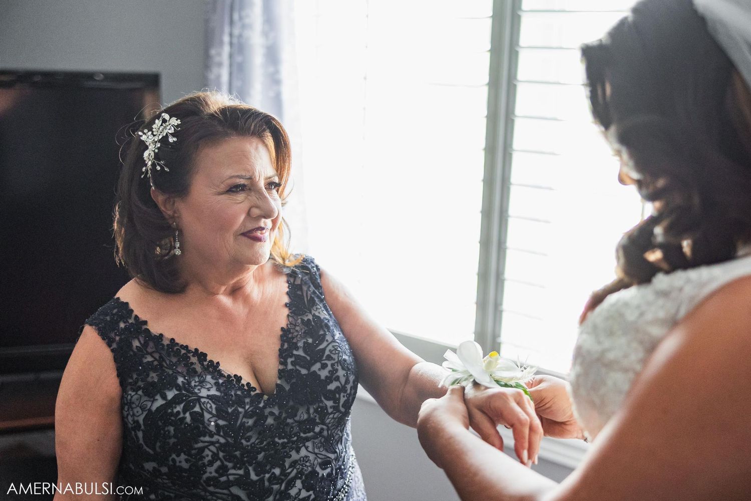 Two people in formal attire having an intimate moment in a sunlit room.