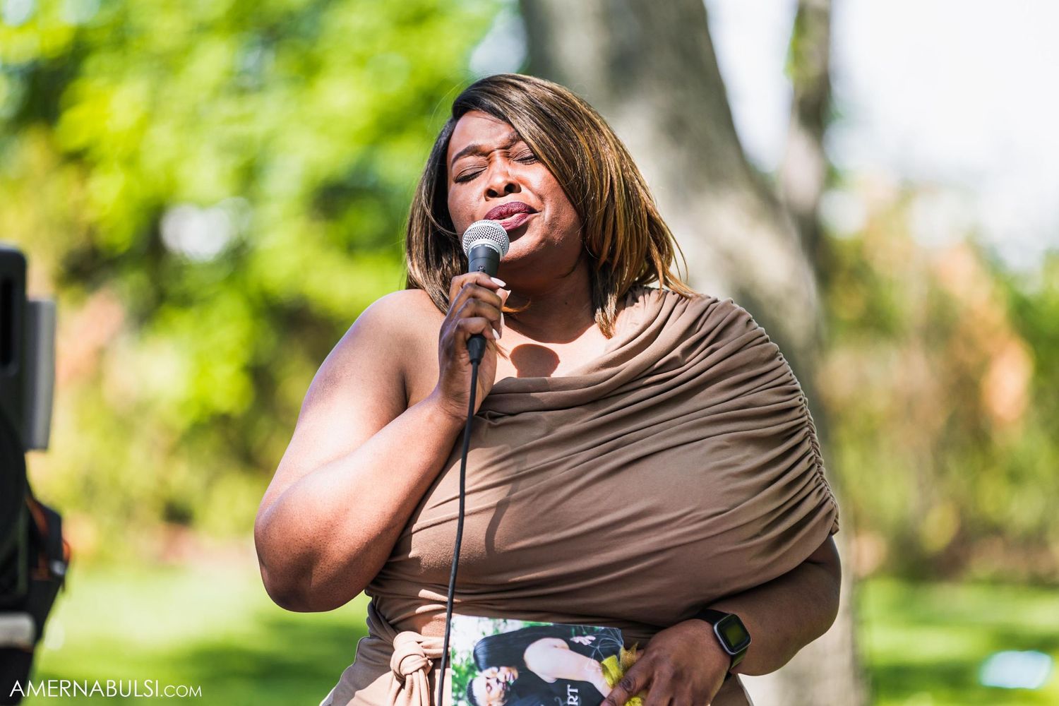 Wedding singer performs emotionally during outdoor reception with microphone.