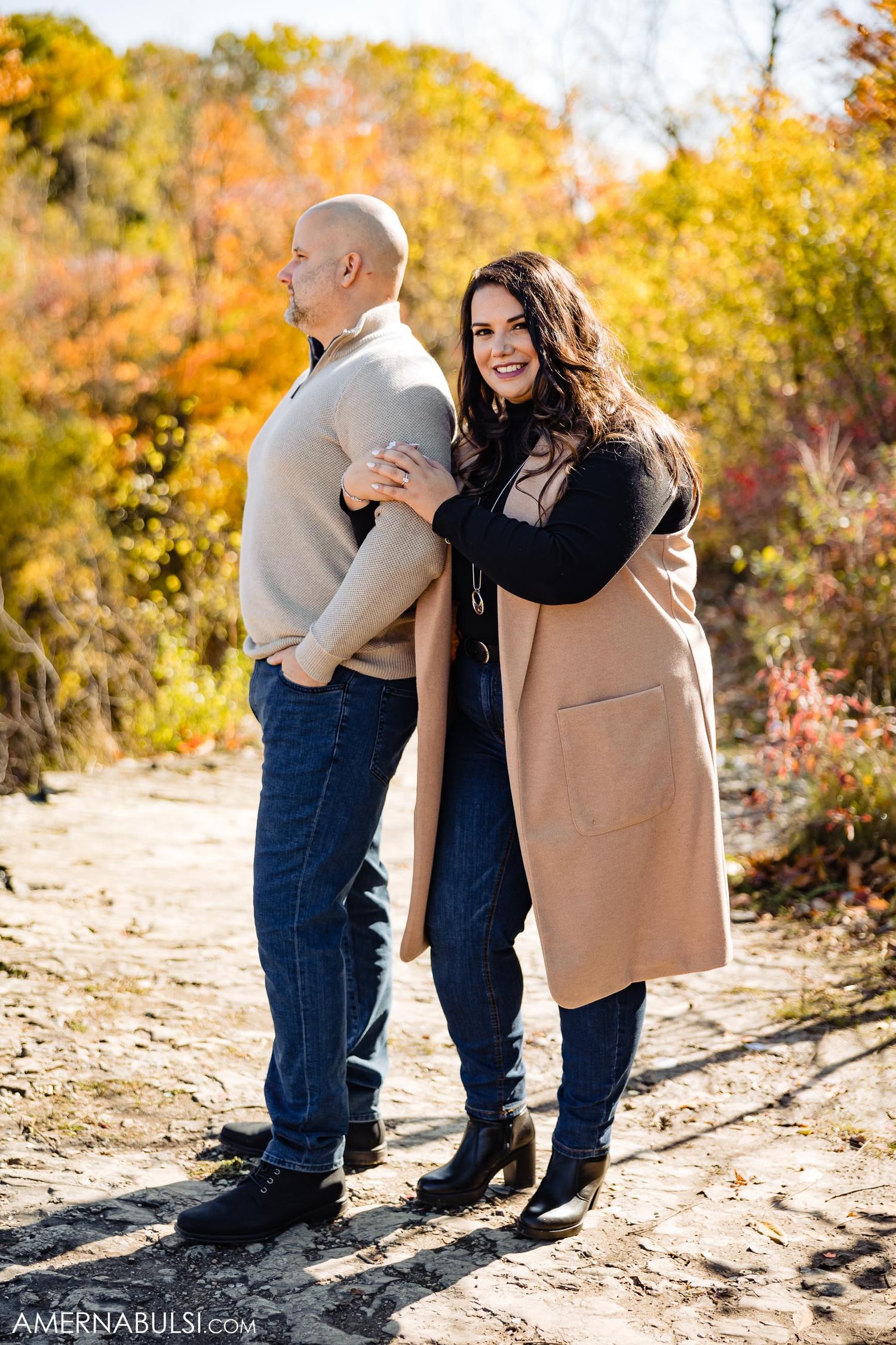 Casual outdoor portrait in autumn sunlight with tan coat and fall colors.