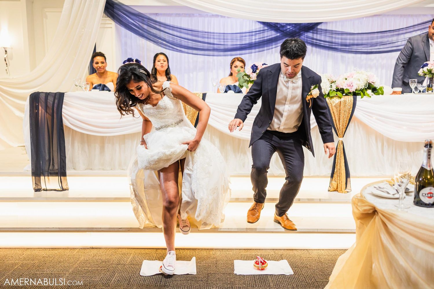 Wedding couple performs fun dance moves on an elevated platform during their reception.