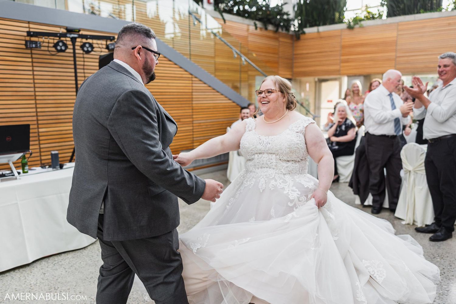 A couple in formal attire sharing their first dance in a modern reception space.