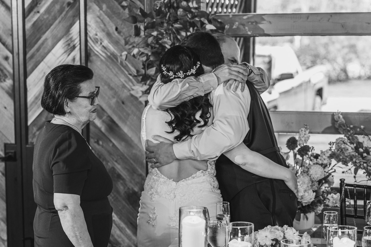 Black and white photo of bride and groom sharing an emotional hug at their wedding reception.