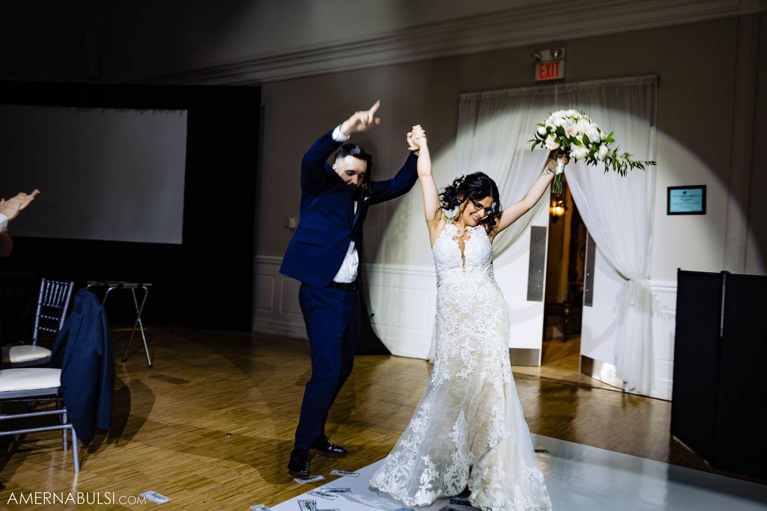 A joyous first dance moment between newlyweds at their wedding reception with a decorative arch in the background.