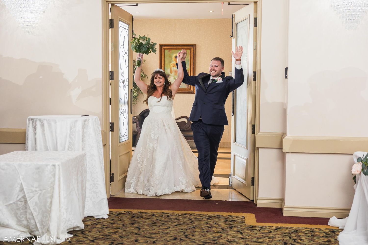 Newlyweds make grand entrance through doorway at wedding reception.