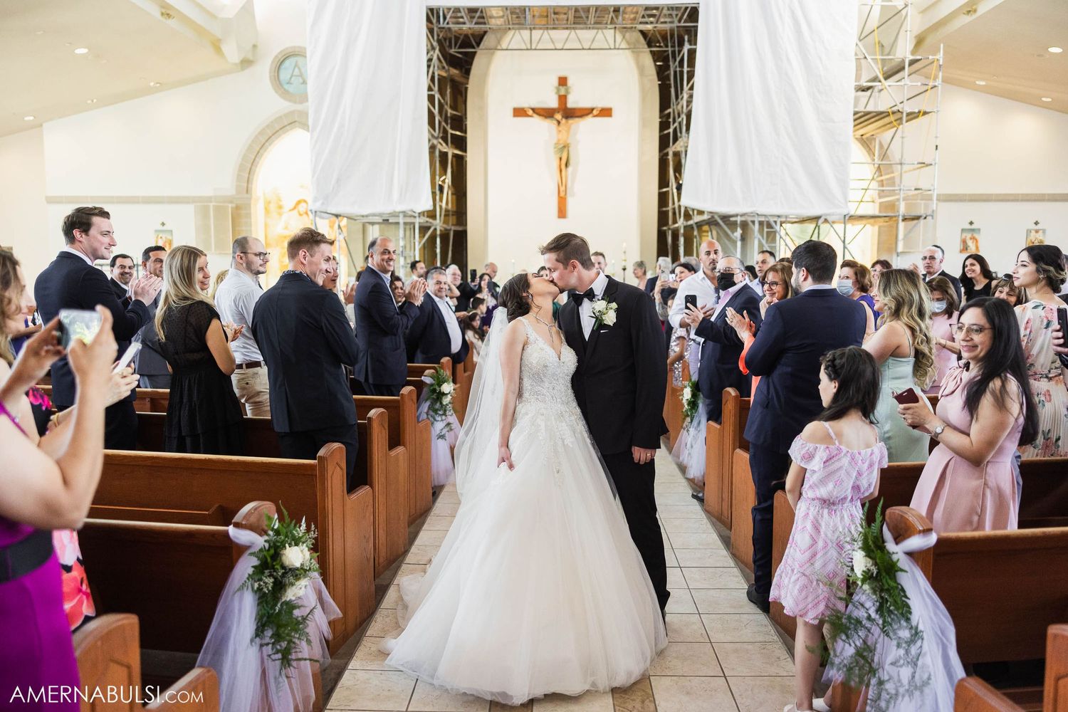A joyous wedding recessional in a church filled with guests and floral decorations.