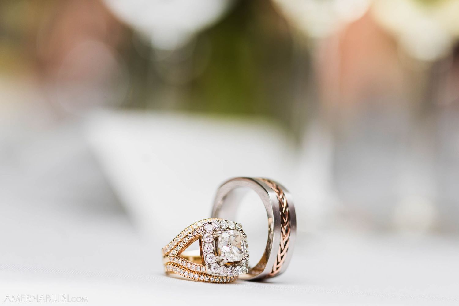 Close-up of an elegant diamond engagement ring with intricate metalwork design on blurred background.