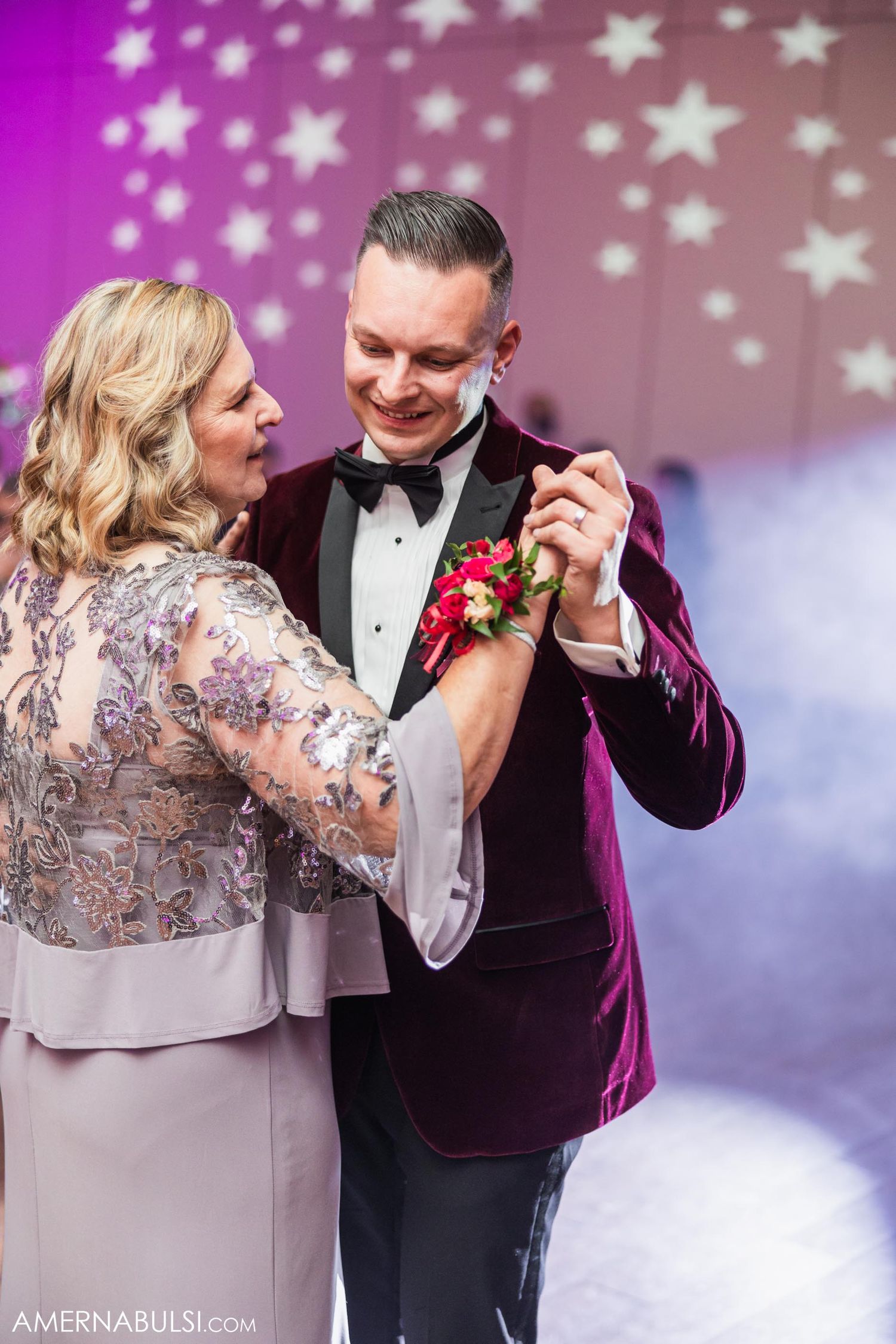 Elegant couple sharing intimate dance moment under starlit backdrop at formal event.