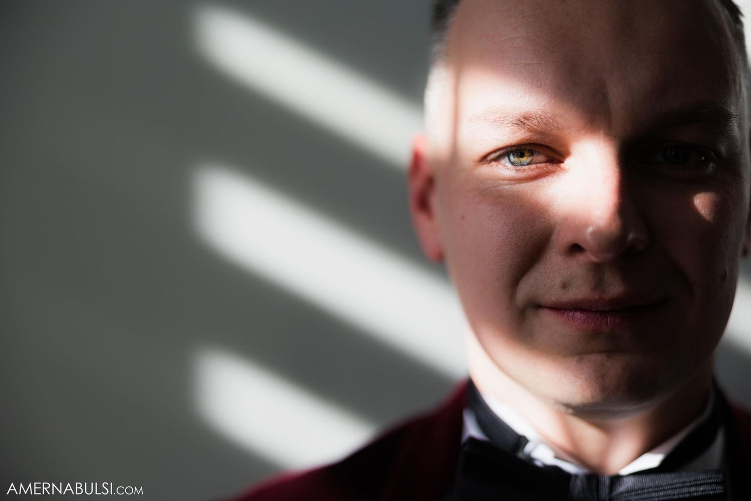 Dramatic portrait with window light casting shadows across a formal attire.