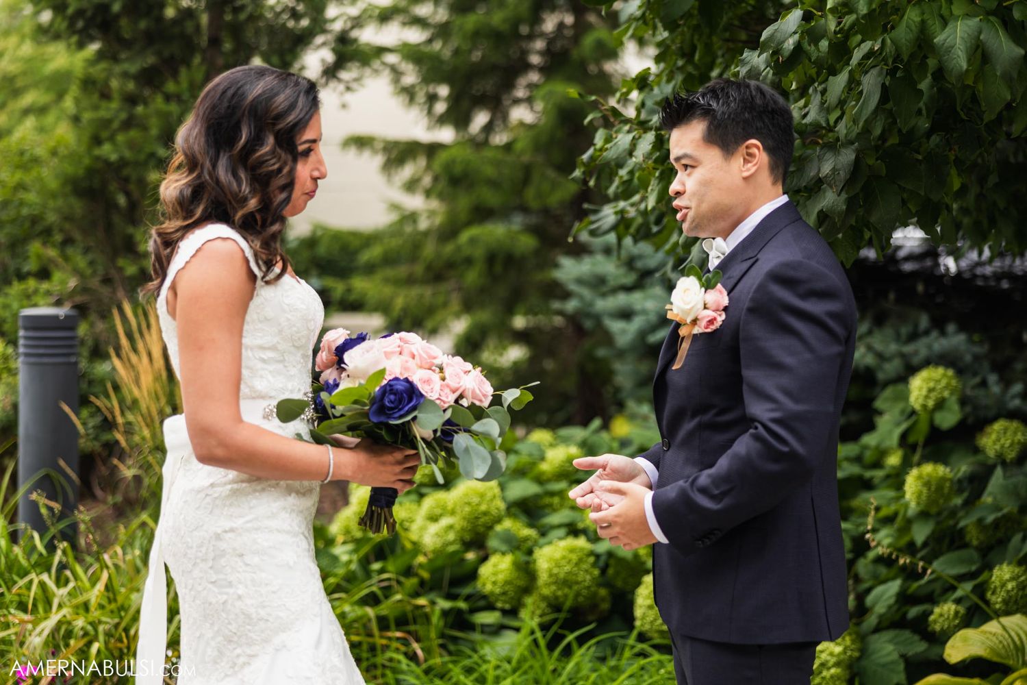 First look moment between couple in garden setting with bouquet.