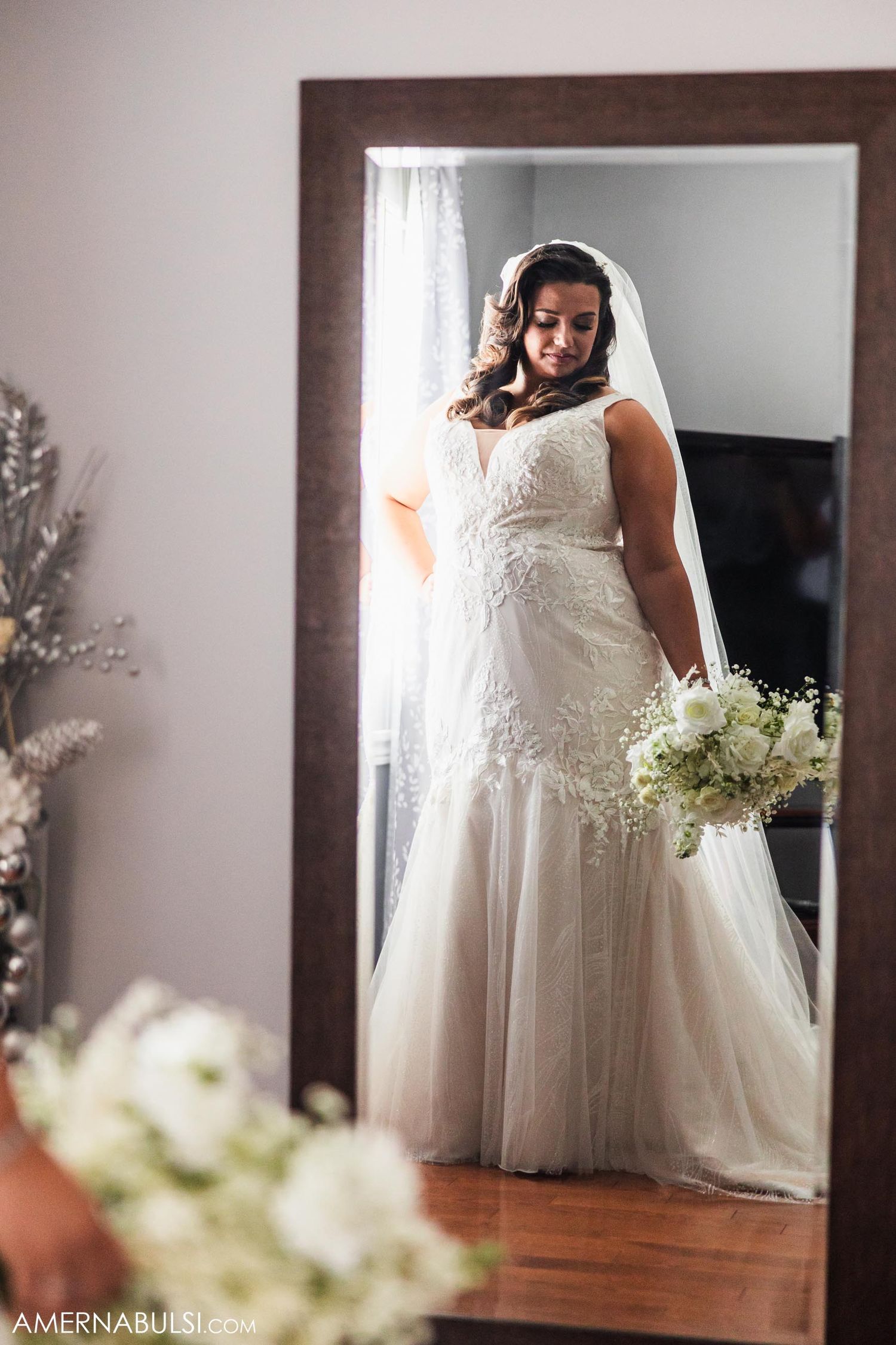 Wedding dress reflection in full-length mirror with delicate lace details and flowing train.