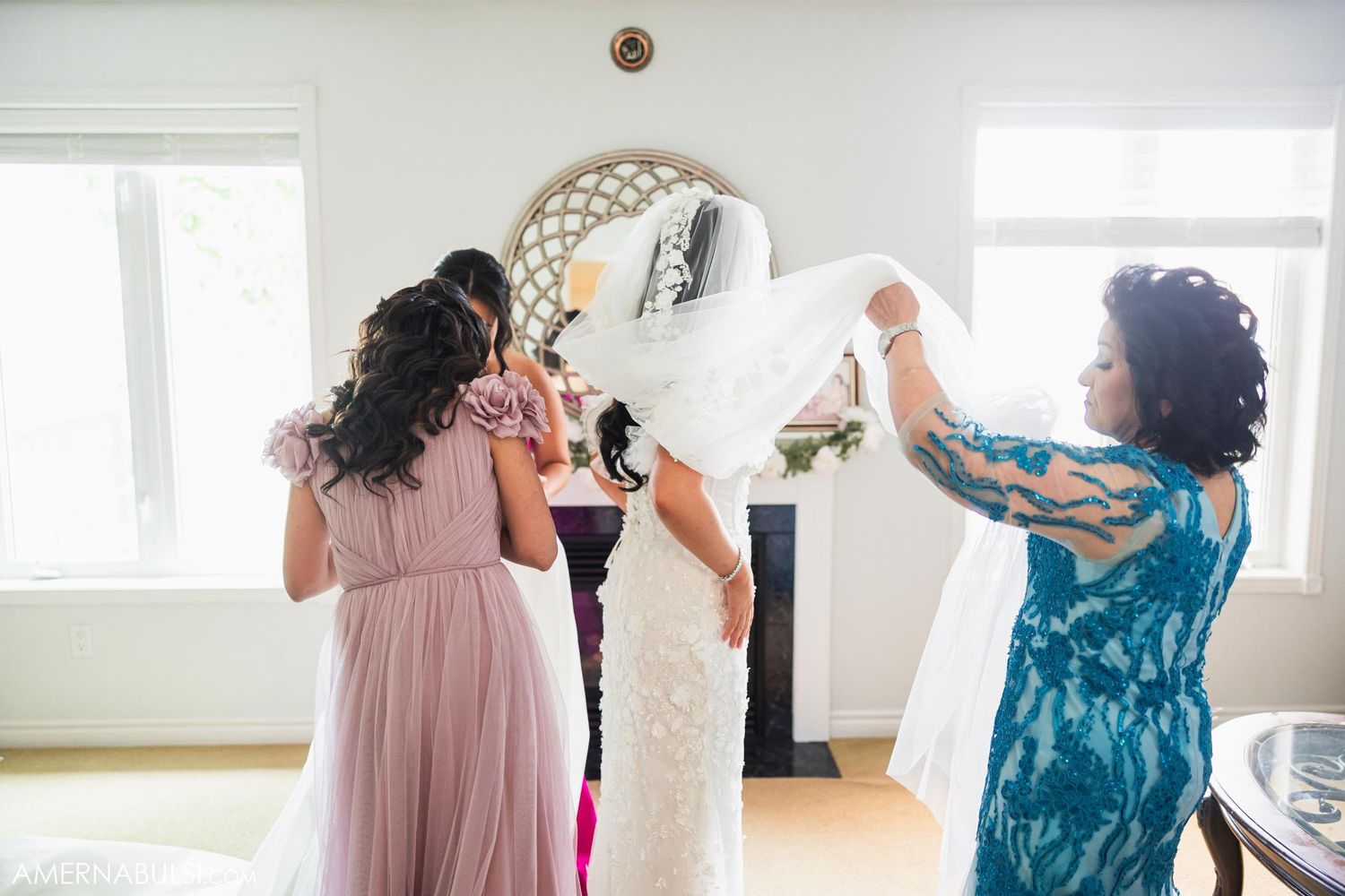 Wedding preparations in bright room as attendants help with bridal styling.
