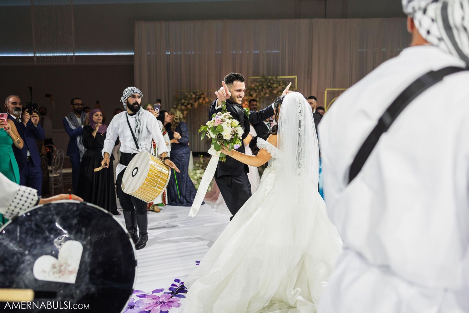 Wedding musicians playing drums while couple celebrates on dance floor.