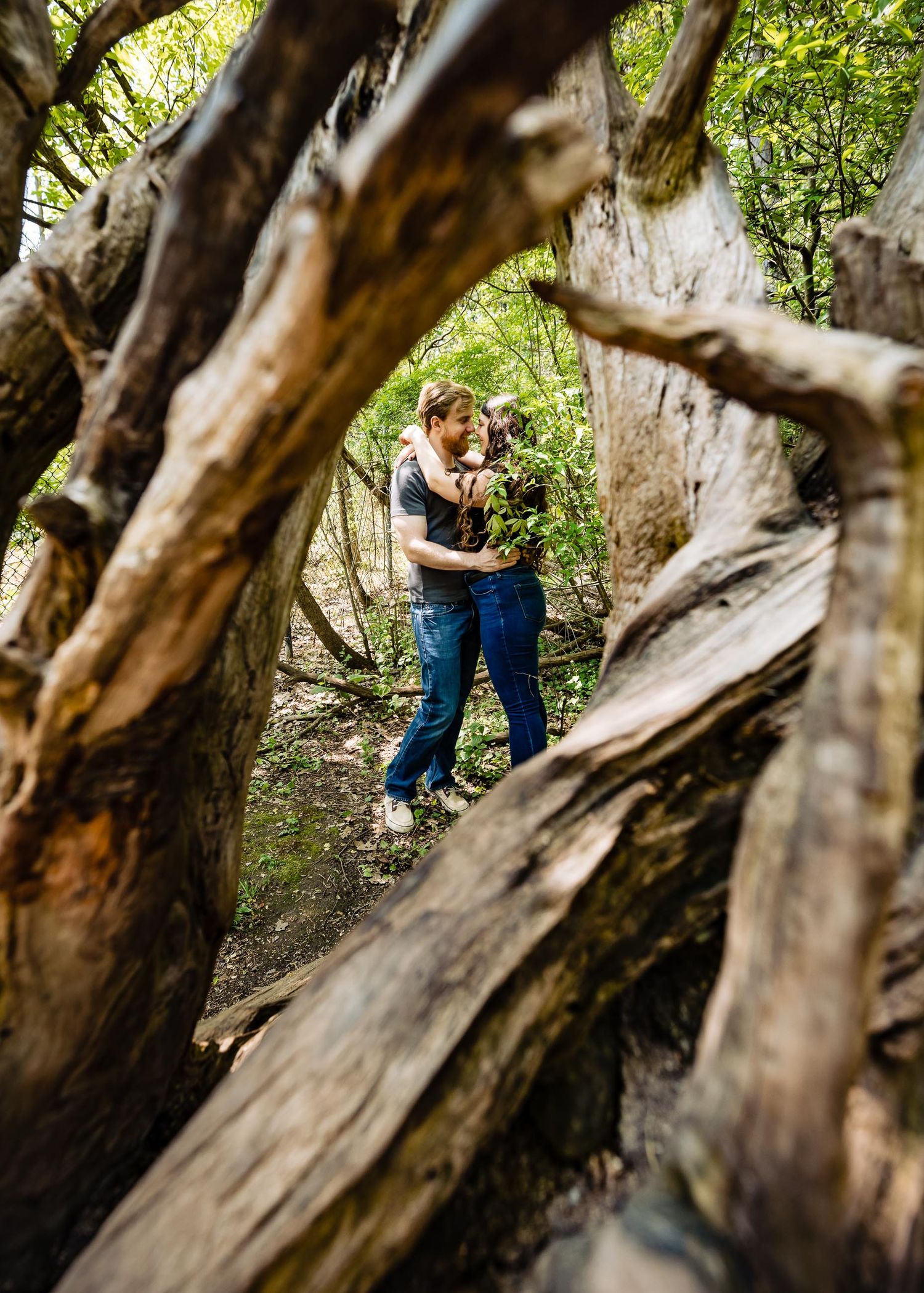 Intimate moment captured through natural wooden frames in forest setting.