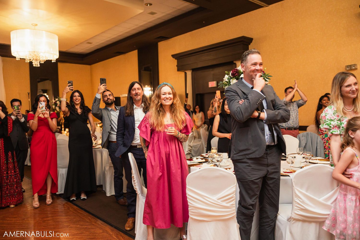 Wedding guests gathered in formal attire watching entertainment at an elegant reception venue.
