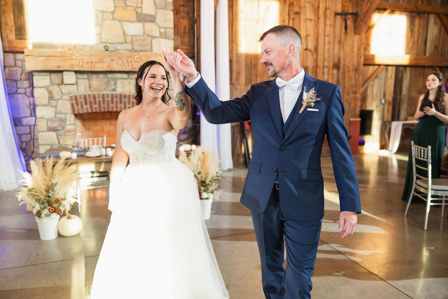 Newlyweds celebrate with joy during their reception dance in a rustic barn setting.