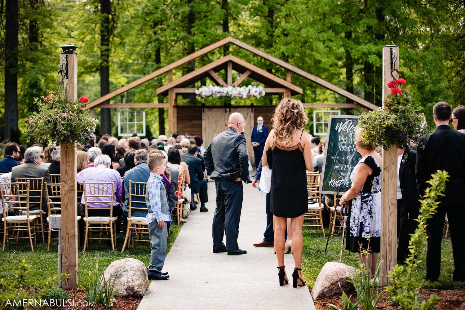 Wedding ceremony setup in a rustic outdoor venue with wooden pergola and guest seating.