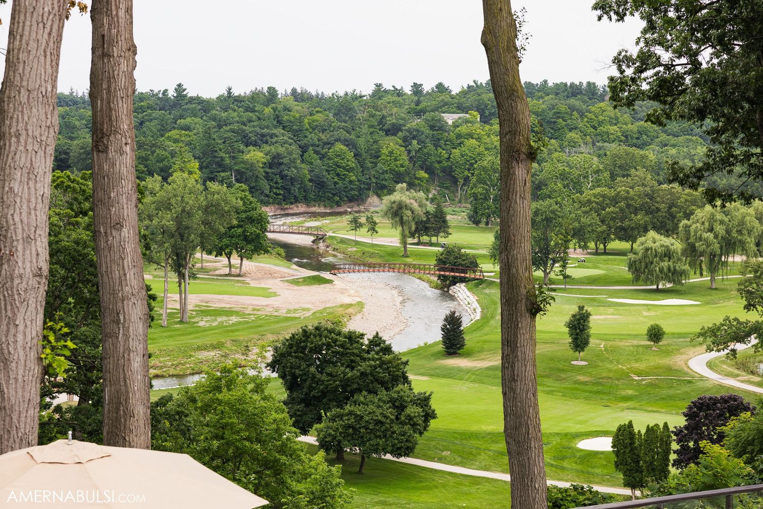 Scenic aerial view of winding golf course with trees, greens and pathways.