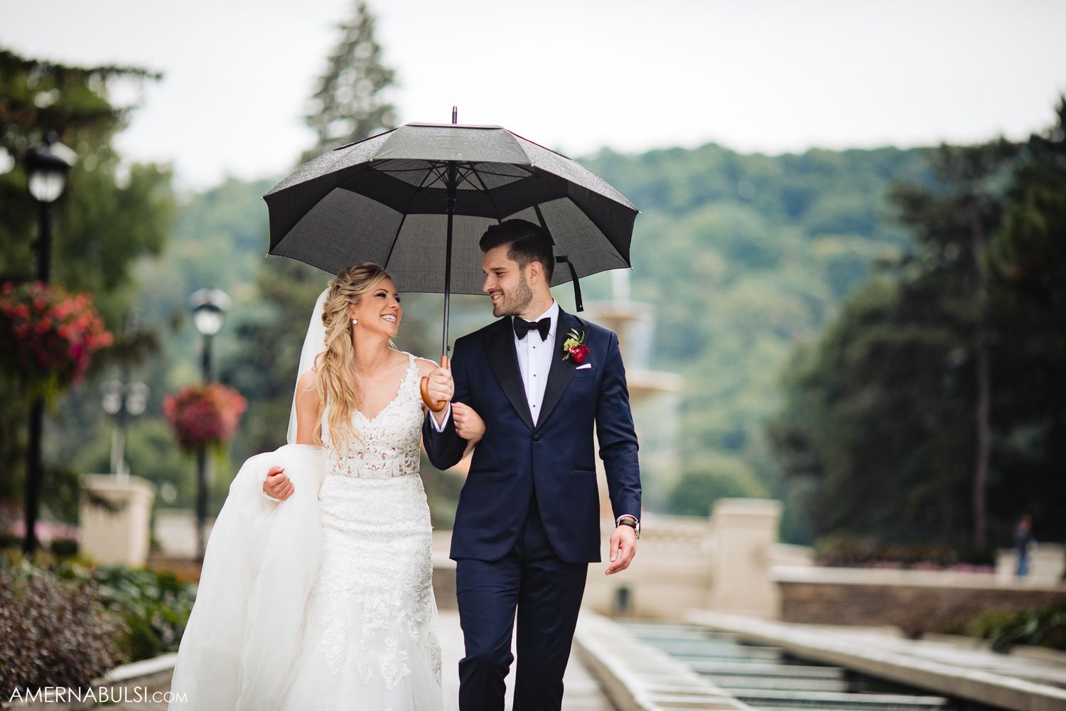 A couple shares romantic moments under umbrellas on their rainy wedding day.