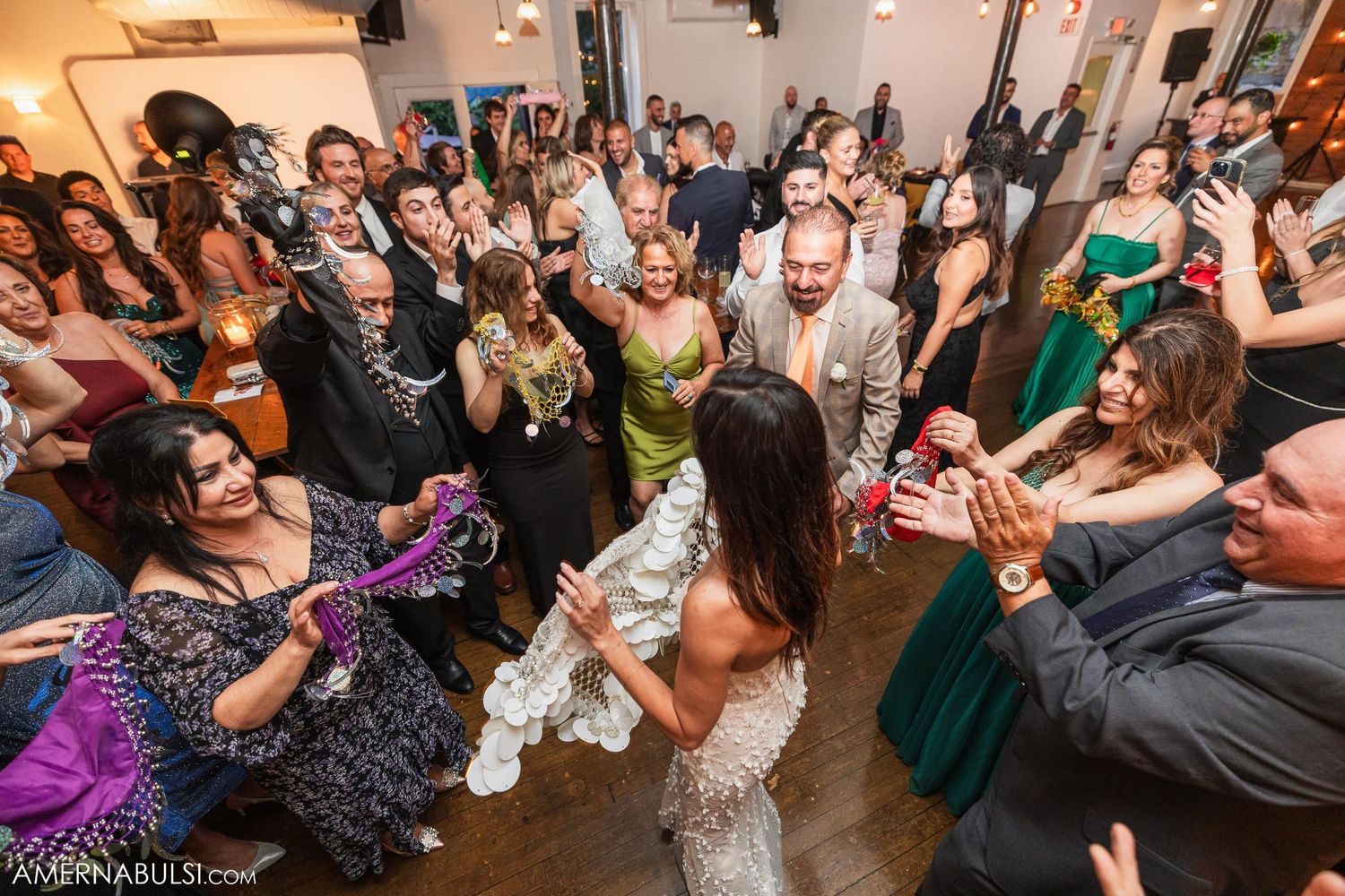 Large group of wedding guests dancing and celebrating on a crowded dance floor.