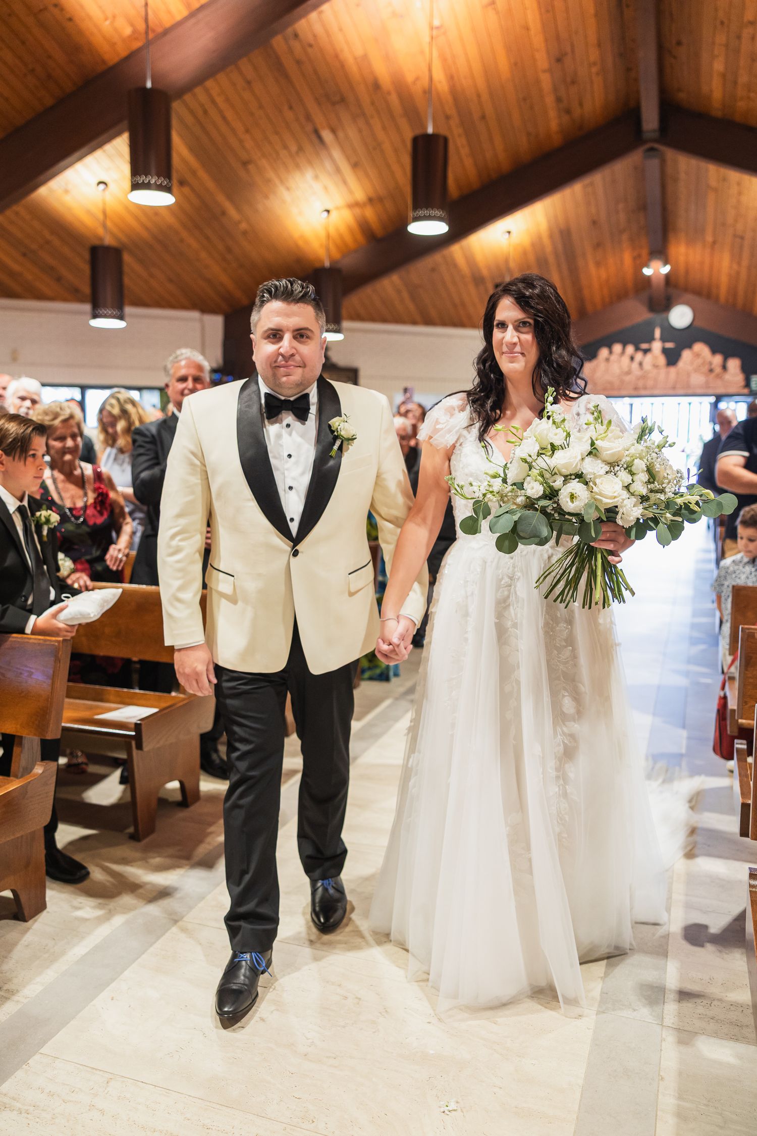 Bride and groom walk hand-in-hand down the aisle after their church wedding ceremony.