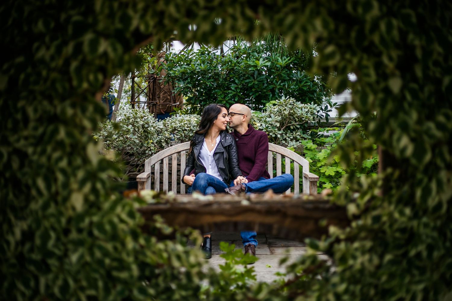 Romantic garden engagement session with couple framed by lush greenery and natural archways.