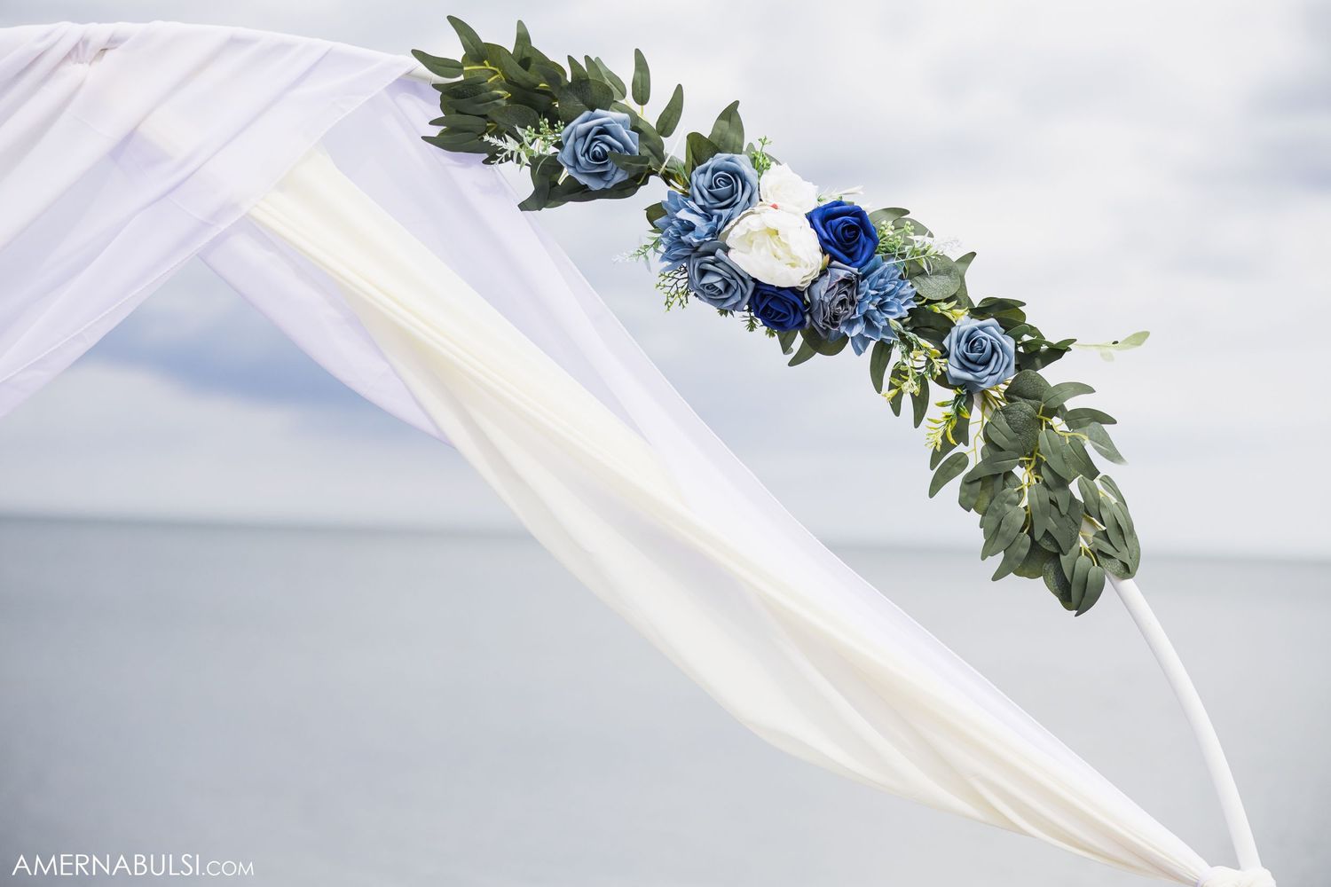 Delicate floral details with white fabric and blue flowers create an ethereal wedding backdrop.